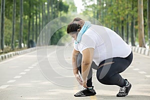 Fat woman tying her shoelaces on the road photo