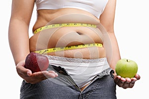 Fat woman with unzip jeans holding apple