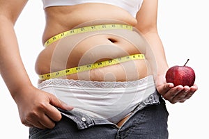 Fat woman with unzip jeans holding apple