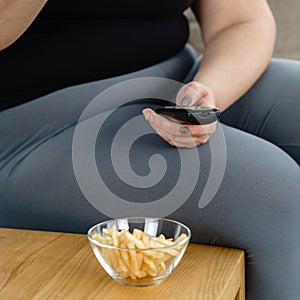 Fat woman watching series at tv eating junk food