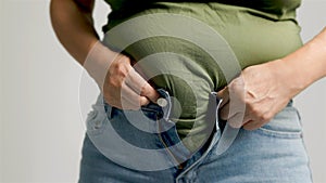 Fat woman zipping up trousers, excess belly fat, unhealthy lifestyle