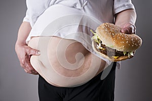 Fat women suffer from obesity with big hamburger in hand, junk food concept