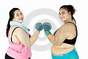 Fat women train with dumbbells on studio