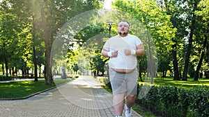 Fat young man jogging in park, obesity concept, struggling with insecurity photo