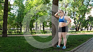 Fat young women resting after hard training in park, struggling with obesity