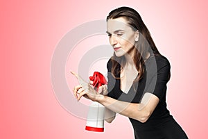 The fatal woman in a black dress with a spray for washing glasses pretending to be a secret agent, holding a spray like a gun.