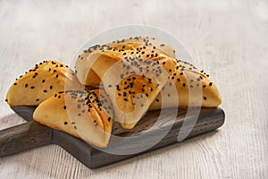 Fatayer samosa with white cheese and black sesame seeds on wooden board