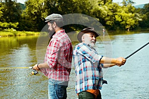 Father and adult son fishing in lake. Family time. Man bearded fisher. Fishing team. Big game fishing. Retired bearded