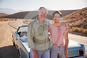 Father and adult son on road trip standing by car, close up