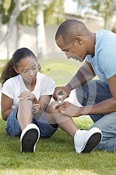 Father Applying Bandage On Daughter's Knee