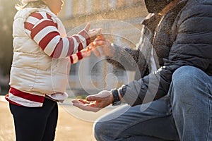 Father applying sanitizing spay on child`s hands. Personal hygiene during pandemic. Coronavirus prevention spread