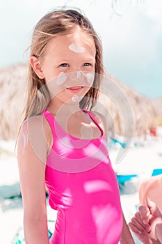 Father applying sun cream to daughter nose.