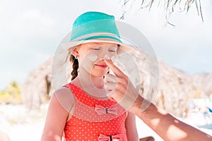 Father applying sun cream to daughter nose.