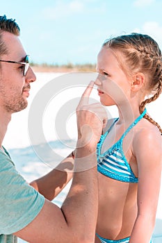 Father applying sun cream to daughter nose.