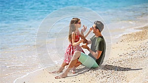 Father applying sun cream to daughter nose.