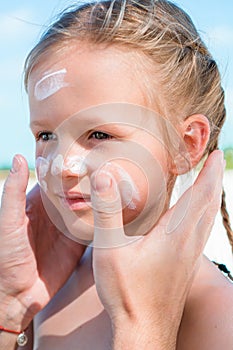 Father applying sun cream to daughter nose.