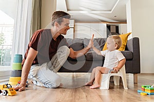 Father assisting his little boy sitting on pot in potty training giving high five to his dad