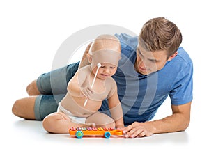 Father and baby boy have fun with musical toys. Isolated on wh