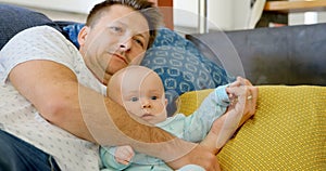 Father and baby boy watching television in living room 4k