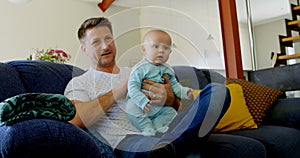 Father and baby boy watching television in living room 4k