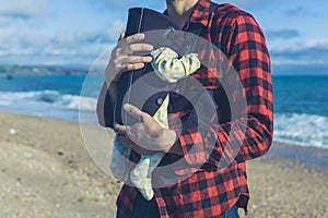 Father with baby in carrier on beach