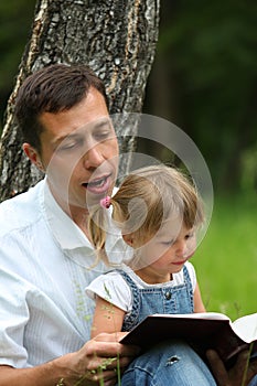 Father with baby daughter reading the Bible