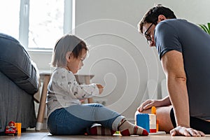 Father and baby girl playing on the floor in the living room. Building blocks game. Bonding time