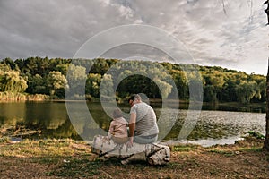 Father and baby girl sitting near lake. Local travel. New normal vacation. Father`s day