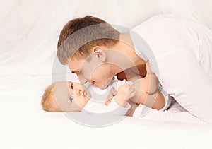 Father and baby at home lying on bed together bedtime