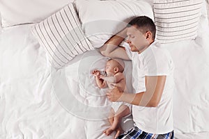 Father and baby sleeping on bed together, top view. Space for text