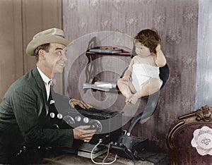 Father with baby in speaker horn of old radio