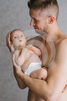 Father with a beard holds a newborn in his arms on a grey background. Holiday concept Father`s Day