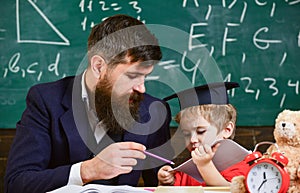 Father with beard, teacher teaches son, little boy. Individual schooling concept. Kid studies individually with teacher