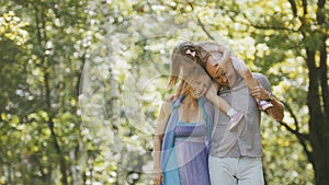 Father - bold man, mother - blonde beautiful woman and little girl - walking in the park at sunny day