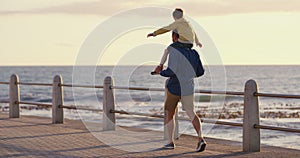 Father bonding with his son while walking by the beach on a fun summer day. Dad playing and spending quality time with
