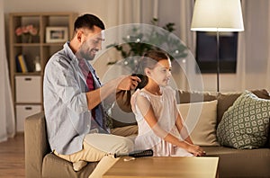 Father braiding daughter hair at home