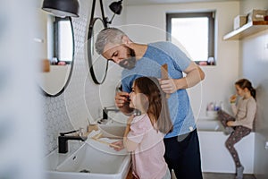 Father brushing his little daughter& x27;s hair in bathroom, morning routine concept.