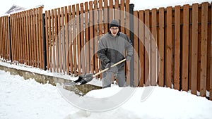 Father is building an ice slide in the yard. A young dad makes a slide of snow for children.