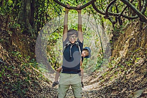 The father carries his son in a baby carrying is hiking in the forest. Tourist is carrying a child on his back in the nature of Vi