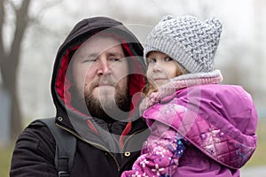 A father carries a satisfied daughter in his arms from a walk in the city park