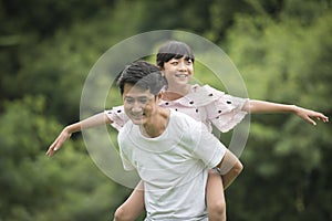 Father carrying daughter on back in the park, Happy family