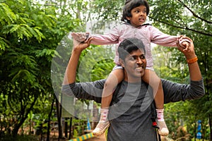 Father Carrying Daughter on Shoulders in park.dng