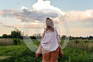 Father carrying his little daughter on shoulders with blue sky background. Happy loving family. Father and daughter