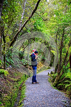 Father is carrying little daughter on his shoulders. Haast, South Island, New Zealand