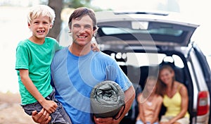 Father carrying son. Portrait of father carrying son and smiling with family sitting in car.