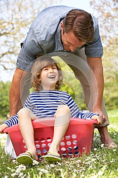 Father Carrying Son Sitting In Laundry Basket