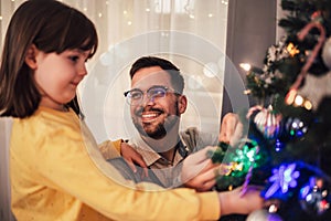 Father celebrates Christmas with his daughter by the beautiful Christmas tree