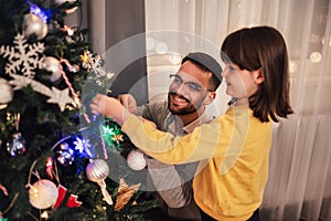 Father celebrates Christmas with his daughter by the beautiful Christmas tree