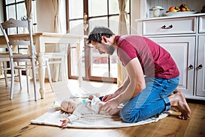 Father changing a baby girl at home.