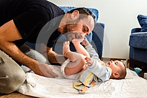 Father changing his baby`s diaper while caressing him affectionately